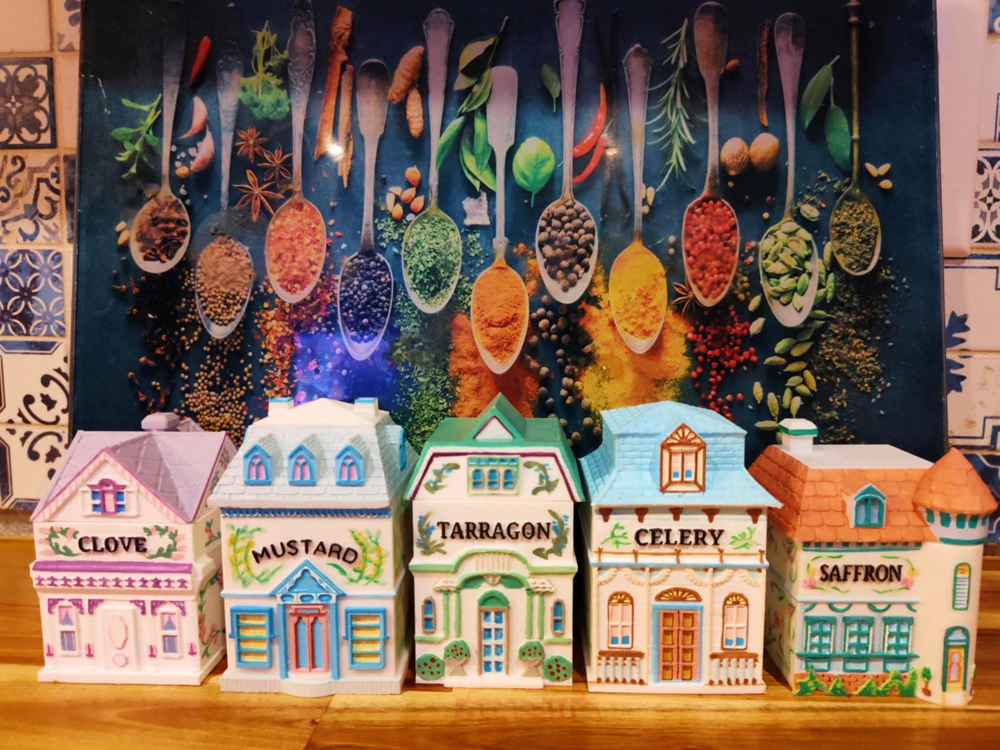 Set of five hand-painted house-shaped spice jars labeled Clove, Mustard, Tarragon, Celery, and Saffron, inspired by Lenox designs, displayed in front of a colorful spice-themed backdrop.